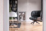 Silk Plaster Prestige 406 in pale cream beside black bookshelves and a dark lounge chair