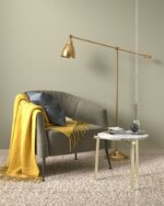 PrimeColor 5 tinted B20 warm greige living room wall with a grey armchair, yellow throw and a brass floor lamp