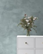 Nappa velvet-touch wall paint in sage grey-green behind a white chest of drawers with cotton stems