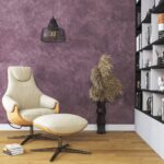Nappa velvet-touch wall paint in dusty plum, cream lounge chair and ottoman under a black pendant