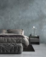 Nappa velvet-touch wall paint in grey-blue, bedroom with grey bedding and a dark bedside table