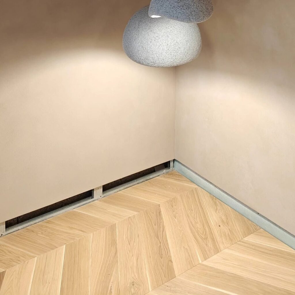Interior room with Travertino Naturale lime plaster walls, pendant lamp and herringbone wood floor — Silk Plaster