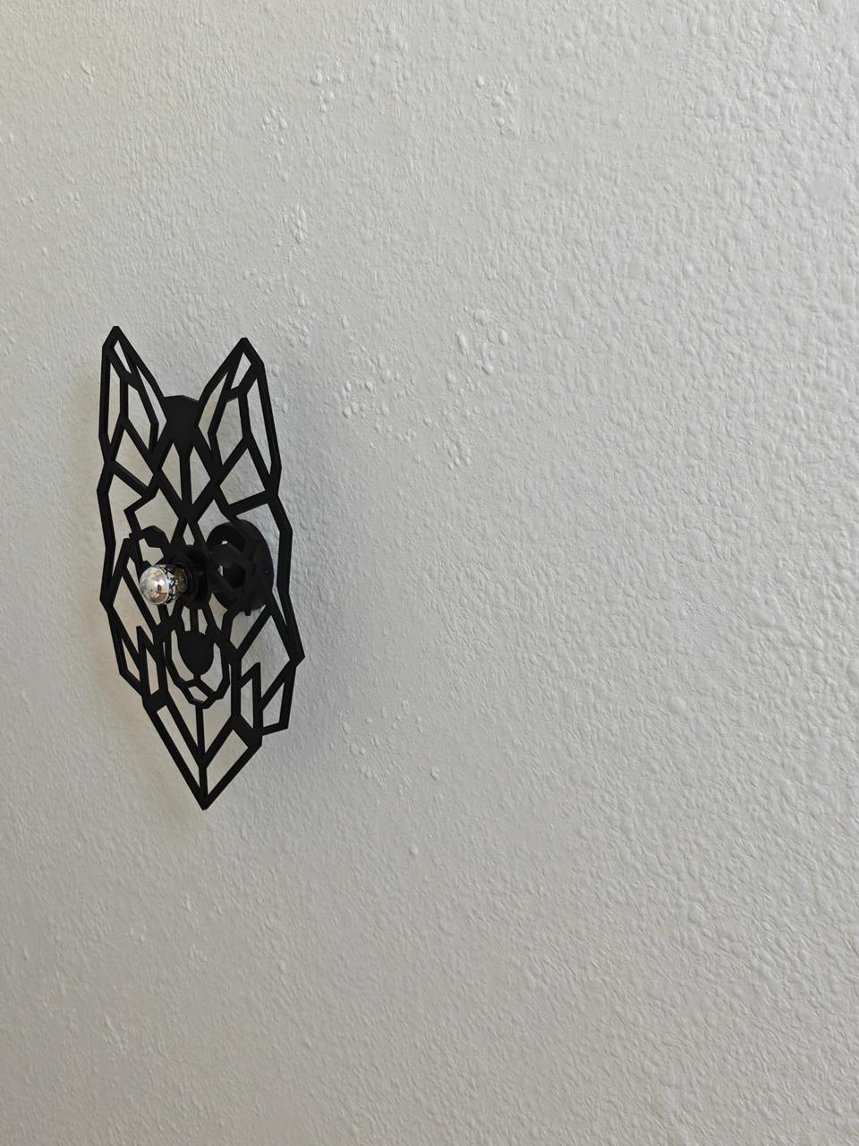 Close-up of a black geometric wolf wall sconce mounted on a Victoria 701 silk plaster wall with visible cotton fibre texture