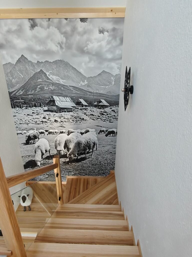 Wide view of a Tatra chalet stairwell finished in Victoria 701 liquid wallpaper with sheep mural and wolf sconce