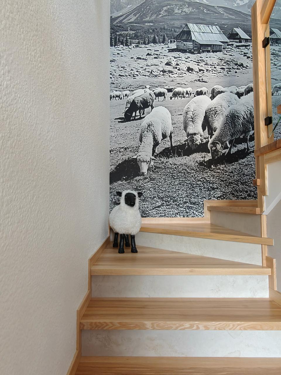 Chalet stairwell with Victoria 701 textile wallpaper, sheep photo mural and a ceramic black-face sheep figurine on the landing