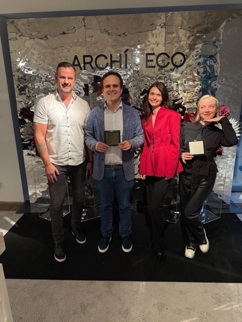 Silk Plaster and Archideco Riga team with recognition awards at the showroom opening in front of the Archideco wall