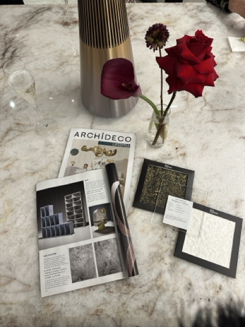 Marble table flat-lay with the Archideco magazine, material sample frames and roses at the Riga showroom