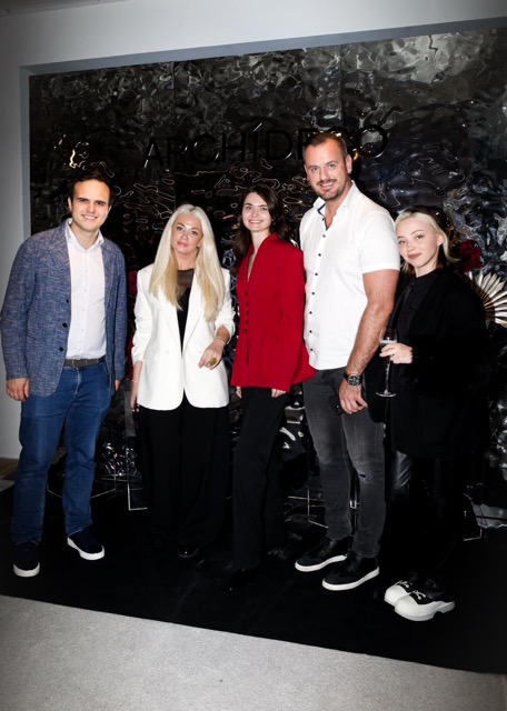 Sandra, Managing Director of Archideco Riga, with the Silk Plaster team at the new showroom in front of a dark decorative plaster feature wall