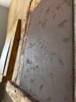 Angled view of a brown taupe Marmorino wall panel showing pitted travertine-style relief