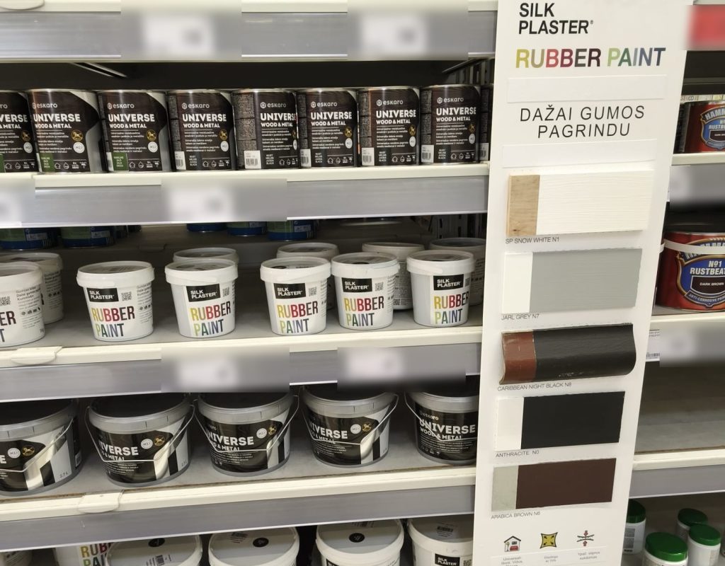 Silk Plaster Rubber Paint buckets on a DIY store shelf next to a tall display stand with painted colour samples