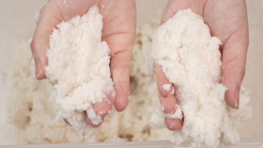 Two hands holding the Silk Plaster cotton and cellulose fibre blend before mixing